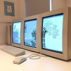 three computer monitors sitting on top of a desk