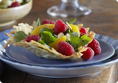 a plate with fruit salad on it next to a bowl of strawberries and cucumbers