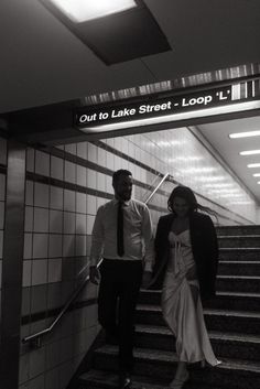 a man and woman are walking down the escalator at lake street loop station