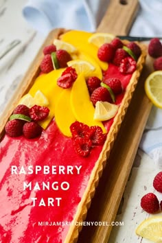 raspberry mango tart on a wooden tray with lemons and raspberries