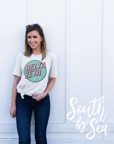 a woman standing in front of a white wall wearing a t - shirt with the words delta zeita on it