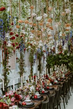 a long table with many flowers hanging from the ceiling and candles on top of it