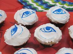 cupcakes with white frosting and blue eyes on them sitting on a red tray