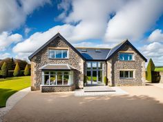 a large stone house sitting on top of a lush green field under a blue cloudy sky