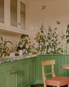 a kitchen with green cabinets and floral wallpaper on the walls, along with a pink chair