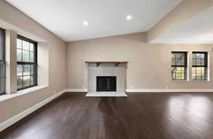 an empty living room with hard wood floors and large windows in the wall, along with a fireplace