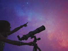 a woman pointing at the stars with a telescope in front of her on a purple and blue background