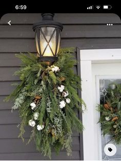 two wreaths hanging from the side of a house next to a door with a light on it