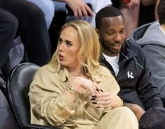 a man and woman sitting next to each other at a basketball game