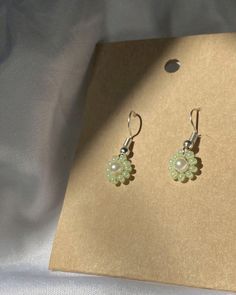 a pair of earrings sitting on top of a brown piece of paper next to a white sheet