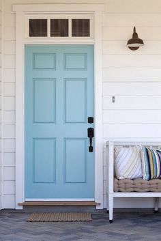 a blue front door with pillows on the bench