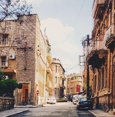 an empty street with cars parked on both sides and buildings in the backround