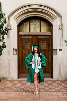 a woman in a graduation gown and cap is standing outside the door of a building