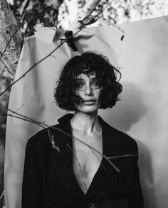 a black and white photo of a woman standing in front of a tree