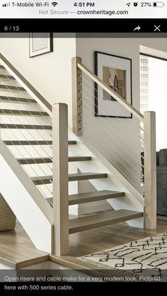 a white stair case in a living room next to a rug and pictures on the wall