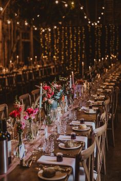 a long table is set up with place settings and flowers in vases on the tables