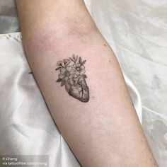 a heart tattoo with flowers on the arm