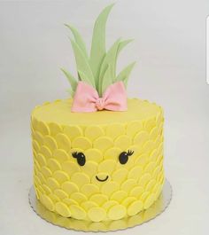 a pineapple cake with a pink bow on it's head, decorated in yellow icing