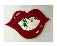 a mirror shaped like a red lips with leaves on the bottom and inside it's mouth