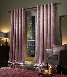 a living room filled with furniture and a large window covered in pink velvet curtains next to a purple rug