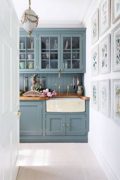 a kitchen with blue cabinets and pictures on the wall above it, along with a chandelier hanging from the ceiling