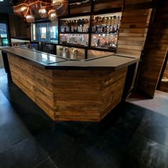 an empty bar with several bottles on the wall and lights hanging from the ceiling above it