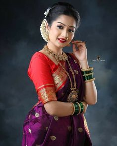 a woman in a purple and red sari with gold jewelry on her neck, posing for the camera