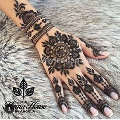 henna tattoo on someone's hand that is black and white with floral designs