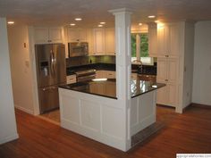 an empty kitchen with white cabinets and stainless steel appliances in the center island, along with hardwood flooring