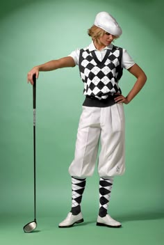 a man in white and black checkered outfit holding a golf club while standing next to a green background