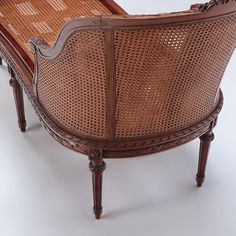 an old wooden chair with wicker back and arm rests on a white surface,