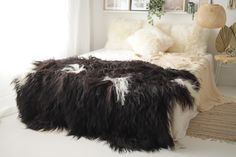 a large furry animal skin blanket on a bed in a room with white walls and flooring