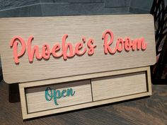 a wooden sign that says phoebe's room open on the side of a table