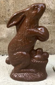 a chocolate bunny statue sitting on top of a stone slab in front of a brick wall