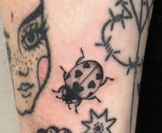 a ladybug tattoo on the leg of a woman's arm and face