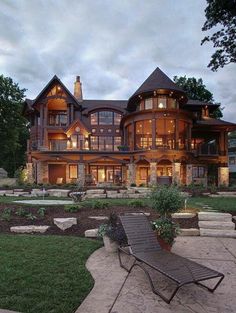 a lawn chair sitting in front of a large house at dusk with the lights on