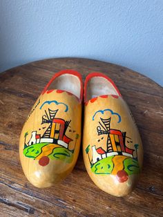 pair of wooden clogs with painted design on them sitting on top of a wooden table