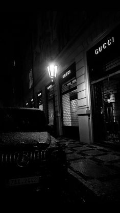 a black and white photo of a car parked in front of a gucci store