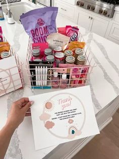 a person is holding up a basket full of items on the kitchen counter with a sign in front of them