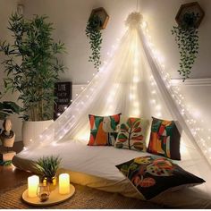 a bed with pillows and lights on the headboard is in front of some plants