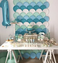 a white table topped with lots of cake and desserts next to a blue balloon