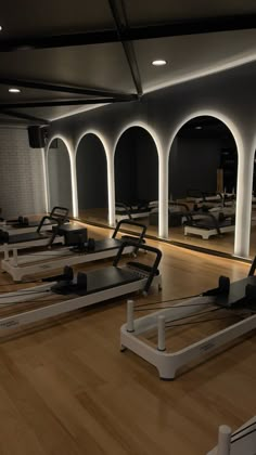 there are rows of treadmills in the gym with mirrors on the wall behind them