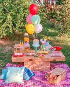 a picnic table with balloons and desserts on it