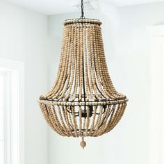 a wooden chandelier hanging from the ceiling in a room with white walls and windows