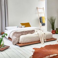 a bedroom with white walls and wooden flooring is decorated in neutral colors, including an animal print rug