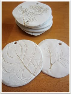 three white ceramic coasters sitting on top of a wooden table