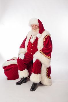 a man dressed as santa claus sitting on top of a red chair in front of a white background