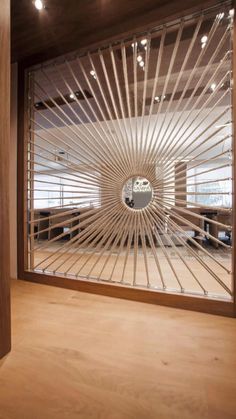 a room with wooden floors and a large window that has a circular mirror on the wall