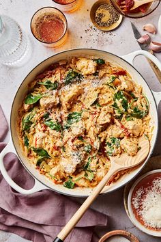 a pan filled with pasta and spinach on top of a table next to other dishes