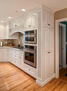 a kitchen with white cabinets and wood floors